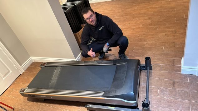 Person giving thumbs up by treadmill.