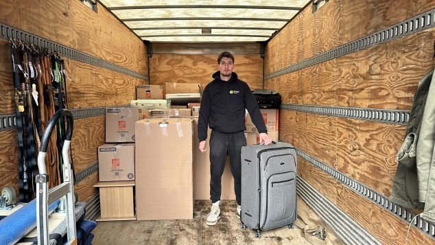 Person standing with suitcase in truck.