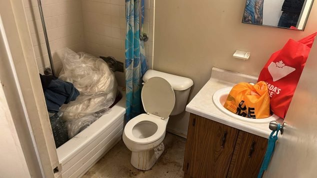 Cluttered bathroom with dirty laundry.