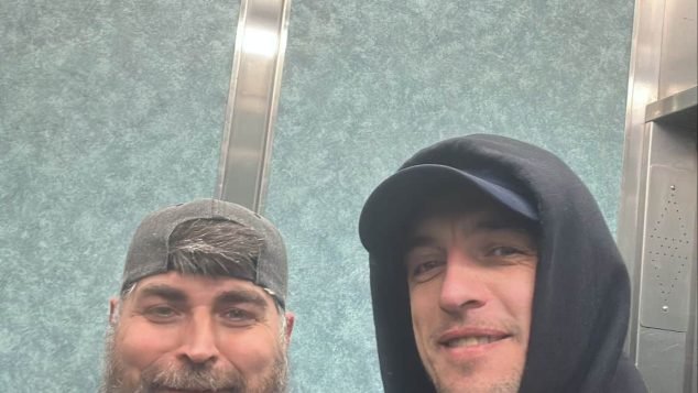 Two individuals posing in an elevator.