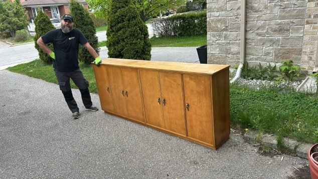 Person standing next to wooden cabinet.