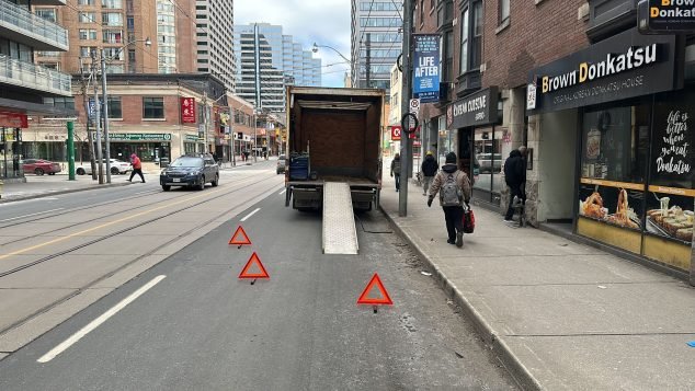Truck unloading on busy city street.