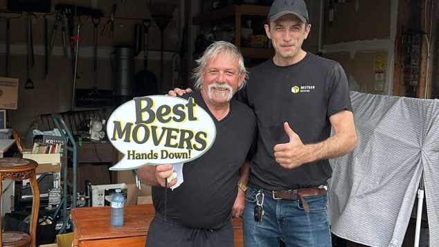 Two movers posing with sign.