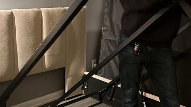 Person assembling a bed frame indoors.