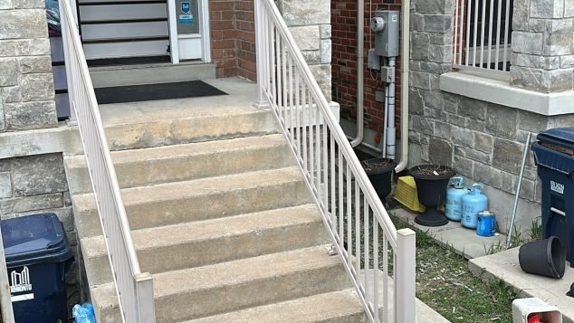 Stairs with railing beside entrance.