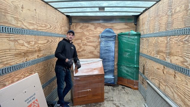 Person inside truck with furniture items.