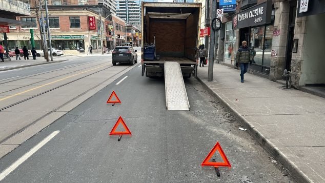 Truck unloading on busy city street.